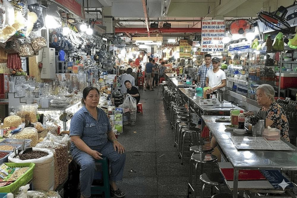 A bustling food court inside An Dong Market with its menu board in Vietnamese